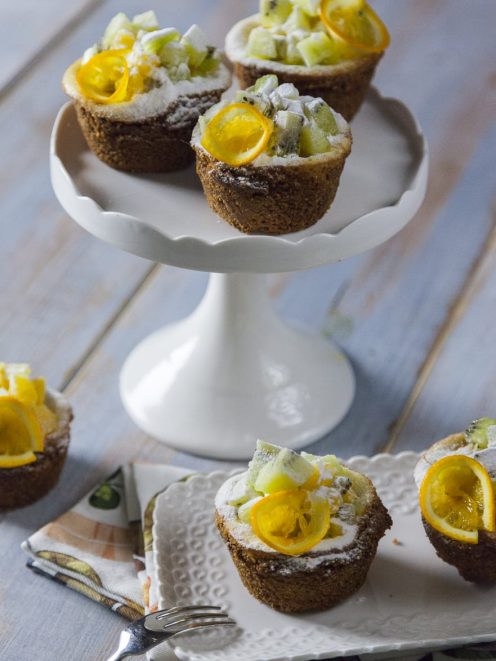 Mini cheesecake con frutta fresca, kiwi a cubetti e fettine di kumquat, spolverizzate di zucchero a velo