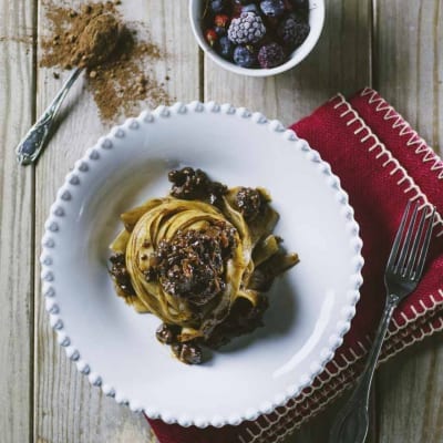 Tagliatelle al ragù di anatra, cacao e frutti rossi servite a nido con salsa scura e bacche