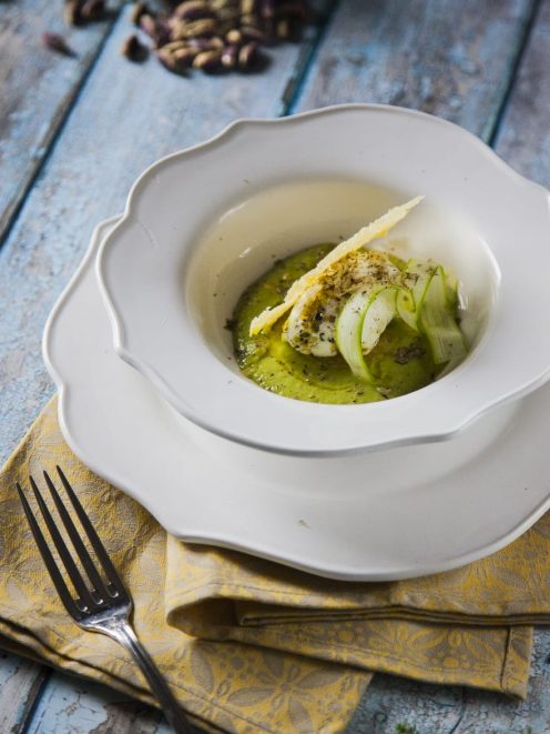 Uovo poché con asparagi su crema verde, guarnito con scaglie di formaggio e zucchine a julienne