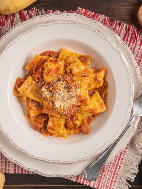 Agnolotti ripieni di patate e pecorino con sugo di pomodoro e formaggio grattugiato