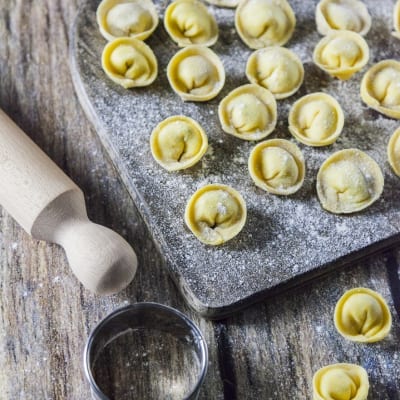 Cappellacci ripieni di ricotta, erba cipollina e lime appena formati e infarinati su tagliere