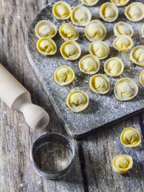 Cappellacci ripieni di ricotta, erba cipollina e lime appena formati e infarinati su tagliere
