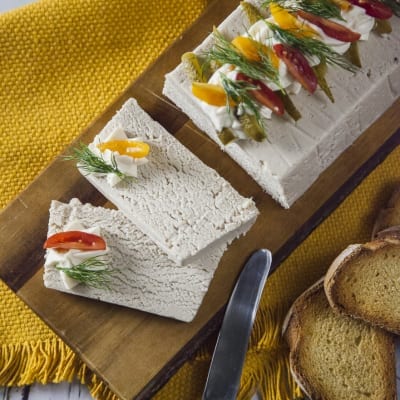 Paté di pollo affettato, guarnito con pomodorini, aneto e cetriolini, servito su tagliere con crostini