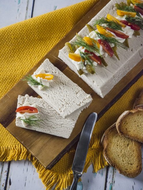 Paté di pollo affettato, guarnito con pomodorini, aneto e cetriolini, servito su tagliere con crostini