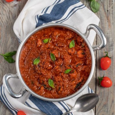Ragù di polpo denso e saporito con salsa di pomodoro e foglie di basilico fresco
