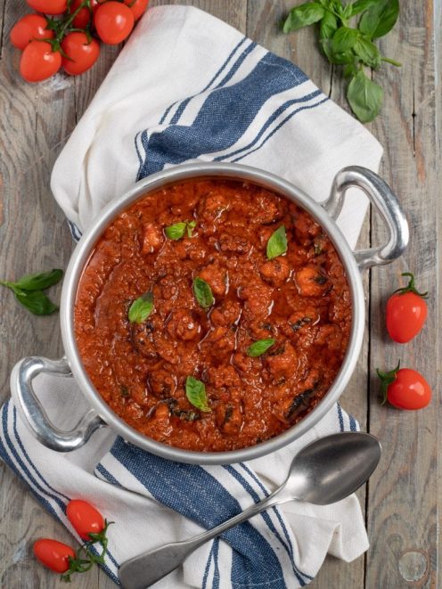 Ragù di polpo denso e saporito con salsa di pomodoro e foglie di basilico fresco