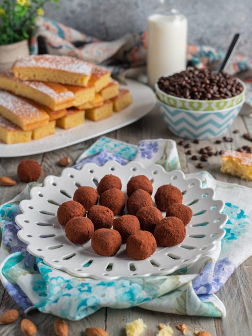 Truffles al caffè ricoperti di cacao amaro, serviti con mandorle e fette di pan di Spagna sullo sfondo