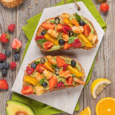 Avocado toast con gamberi, frutti di bosco e pomodorini su pane integrale ai cereali