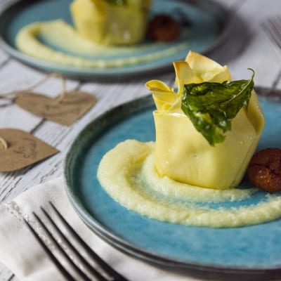 Fagottino di scampi con patate su crema di patate, guarnito con foglie di basilico fritto