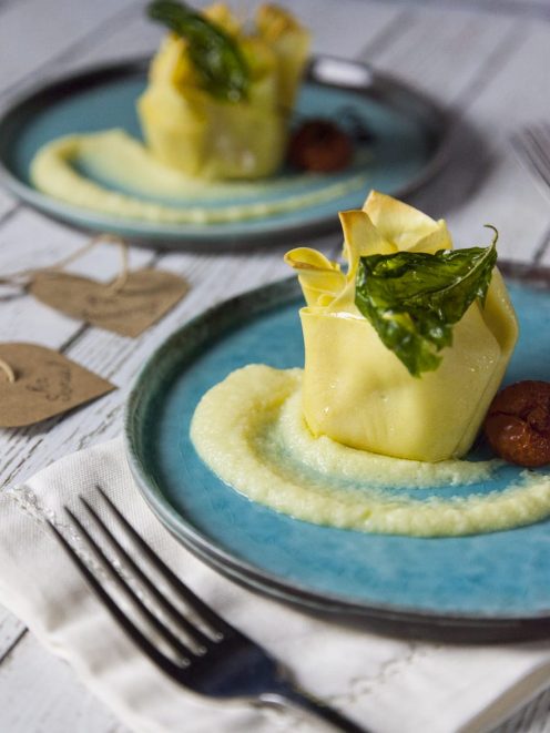 Fagottino di scampi con patate su crema di patate, guarnito con foglie di basilico fritto