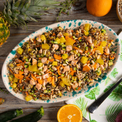 Insalata di quinoa con salmone, carote, zucchine, ananas, arancia e pinoli tostati