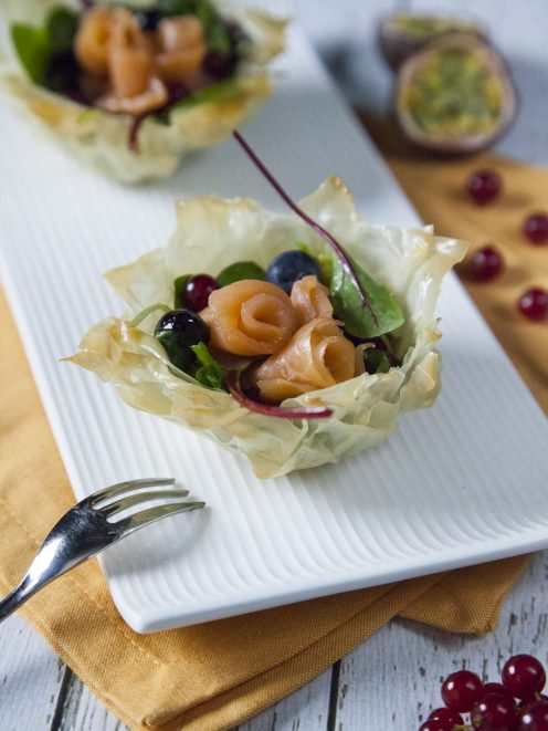 Cestini di pasta fillo con roselline di salmone affumicato, mirtilli, ribes e insalata mista