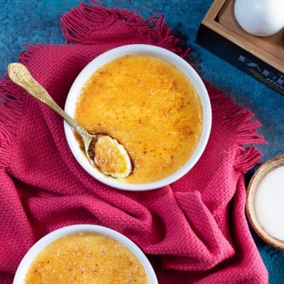 Crème brûlée con crosta di zucchero caramellato e un cucchiaio che rompe la superficie