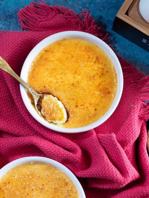 Crème brûlée con crosta di zucchero caramellato e un cucchiaio che rompe la superficie
