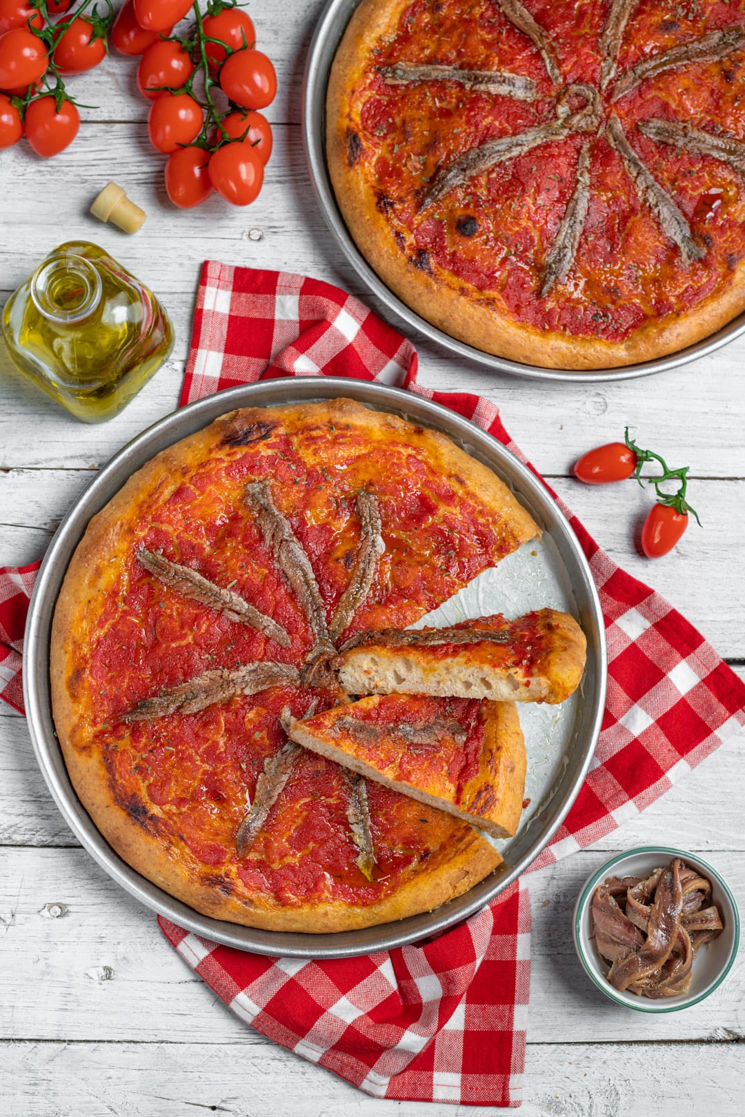 Focaccia integrale alla marinara con fette tagliate, condita con salsa di pomodoro e acciughe disposte a raggiera