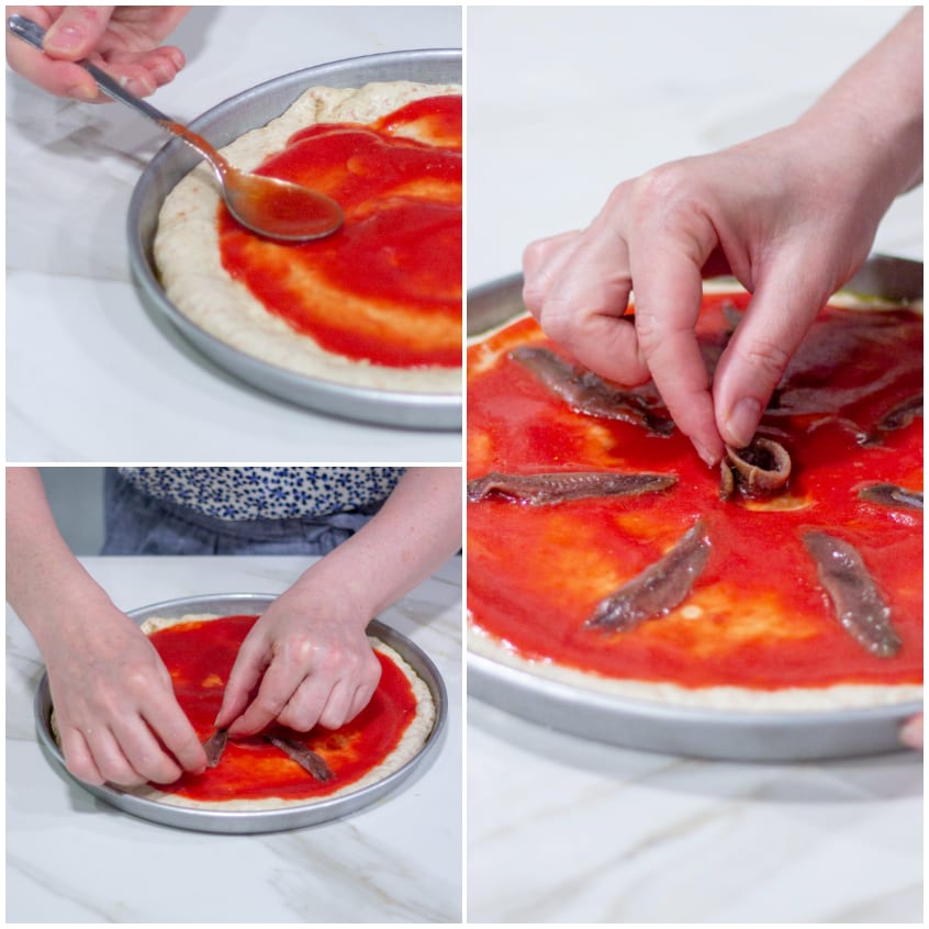 Mani che distribuiscono salsa di pomodoro e acciughe sulla focaccia integrale cruda