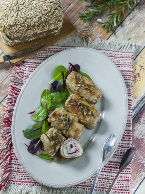 Involtini di manzo con prosciutto e formaggio affettati e serviti con rosmarino e insalatina fresca