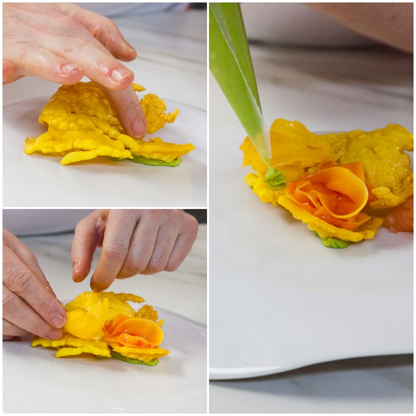 Mani che compongono la millefoglie croccante di riso allo zafferano con fettine di salmone arrotolate e crema di avocado