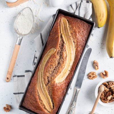Banana bread appena sfornato con banana caramellata in superficie e noci intorno