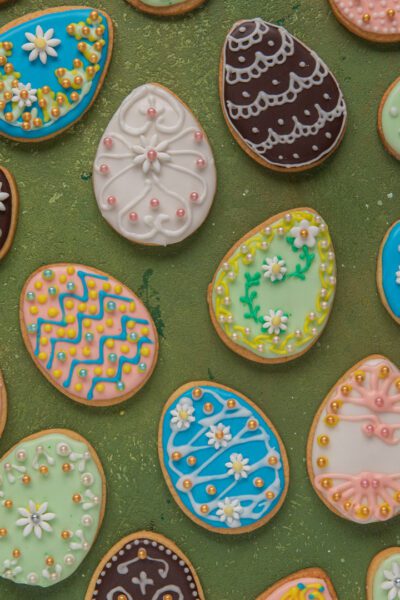 Biscotti di Pasqua a forma di uovo decorati con ghiaccia reale colorata, fiorellini e perline zuccherine