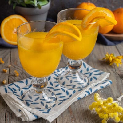 Cocktail mimosa servito in due calici con spicchi d'arancia sul bordo