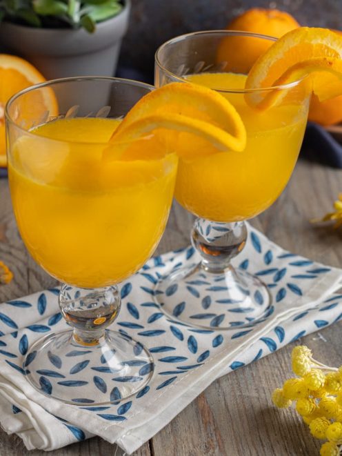 Cocktail mimosa servito in due calici con spicchi d'arancia sul bordo