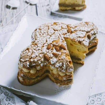 Colomba farcita tagliata a fette, con crema gialla, mandorle e granella di zucchero in superficie