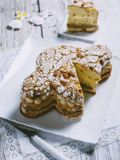 Colomba farcita tagliata a fette, con crema gialla, mandorle e granella di zucchero in superficie