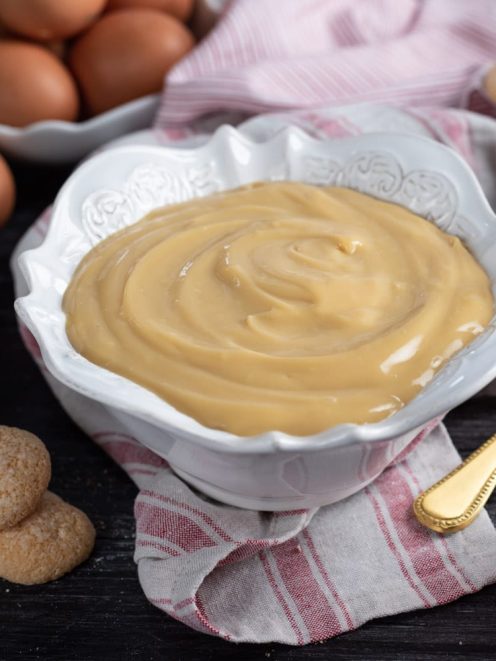 Crema pasticciera allo zabaione liscia e lucida, servita al cucchiaio con savoiardi accanto