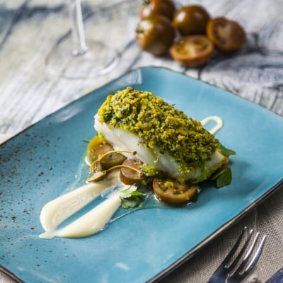 Filetto di merluzzo in crosta di pistacchio su pomodorini e crema, con erbe fresche
