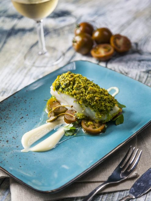 Filetto di merluzzo in crosta di pistacchio su pomodorini e crema, con erbe fresche
