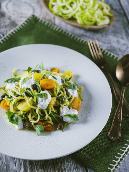 Spaghetti di zucchine con pomodorini gialli, olive, stracciatella e foglie di basilico fresco