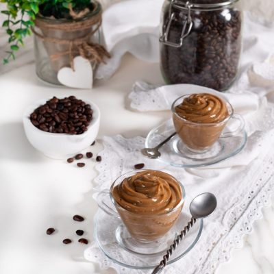 Crema pasticciera al caffè servita in tazzine di vetro con chicchi di caffè sparsi accanto