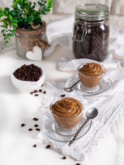 Crema pasticciera al caffè servita in tazzine di vetro con chicchi di caffè sparsi accanto