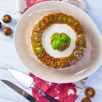 Mousse di tonno decorata con fette di pomodorini neri a spirale e foglie di basilico fresco