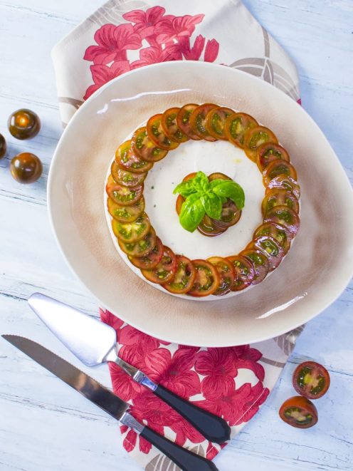 Mousse di tonno decorata con fette di pomodorini neri a spirale e foglie di basilico fresco