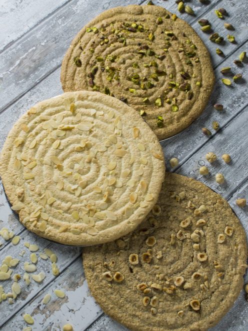 Tre dacquoise con motivo a spirale, guarnite rispettivamente con pistacchi, mandorle a lamelle e nocciole