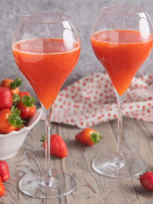 Rossini cocktail servito in due calici con fragole fresche intorno