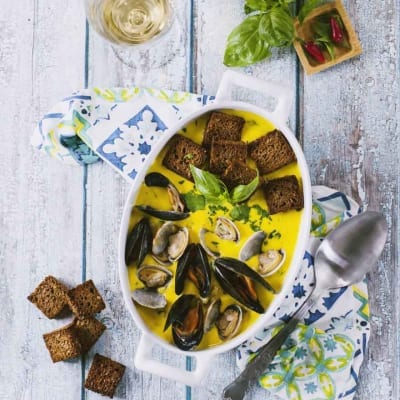 Vellutata con cozze, vongole e zafferano servita con crostini di pane scuro e basilico fresco