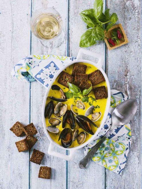 Vellutata con cozze, vongole e zafferano servita con crostini di pane scuro e basilico fresco