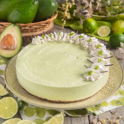 Cheesecake all'avocado con base croccante, mousse verde e ciuffetti di panna decorati con zeste di lime
