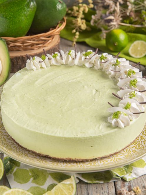 Cheesecake all'avocado con base croccante, mousse verde e ciuffetti di panna decorati con zeste di lime