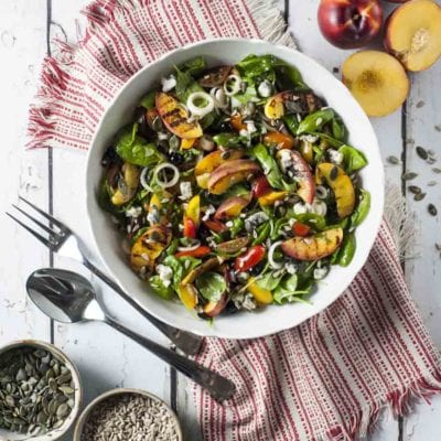 Insalata di pesche grigliate con spinacino, gorgonzola e semi su foglie fresche