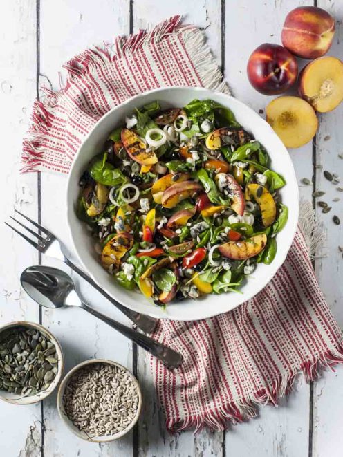 Insalata di pesche grigliate con spinacino, gorgonzola e semi su foglie fresche