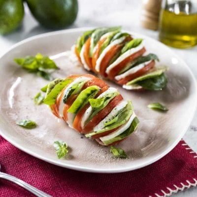 Pomodori hasselback con mozzarella, avocado e foglie di basilico fresco