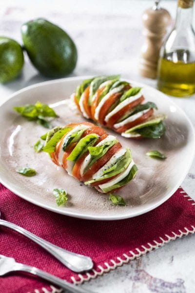 Pomodori hasselback con mozzarella, avocado e foglie di basilico fresco