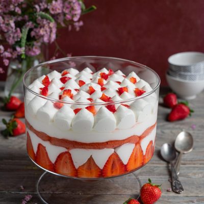 Tiramisù alle fragole a strati con panna montata e fragole fresche a pezzetti in superficie