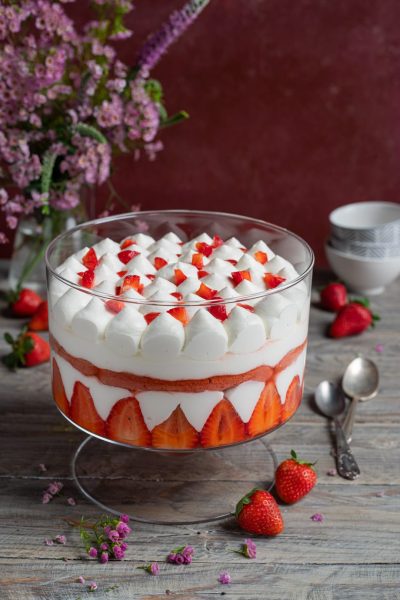 Tiramisù alle fragole a strati con panna montata e fragole fresche a pezzetti in superficie