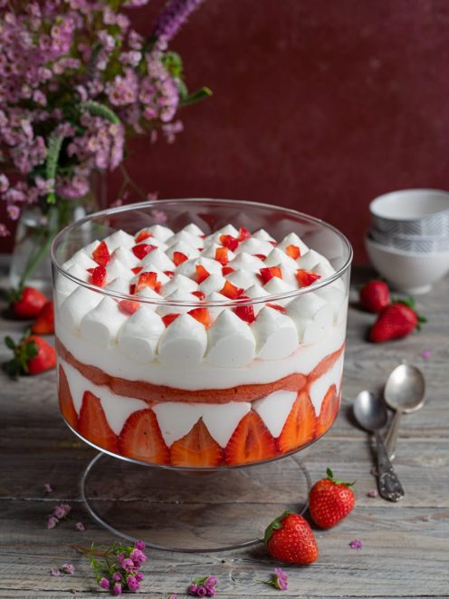 Tiramisù alle fragole a strati con panna montata e fragole fresche a pezzetti in superficie