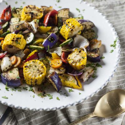 Verdure grigliate con mais, melanzane, zucchine, peperoni e cipolla, cosparse di prezzemolo tritato